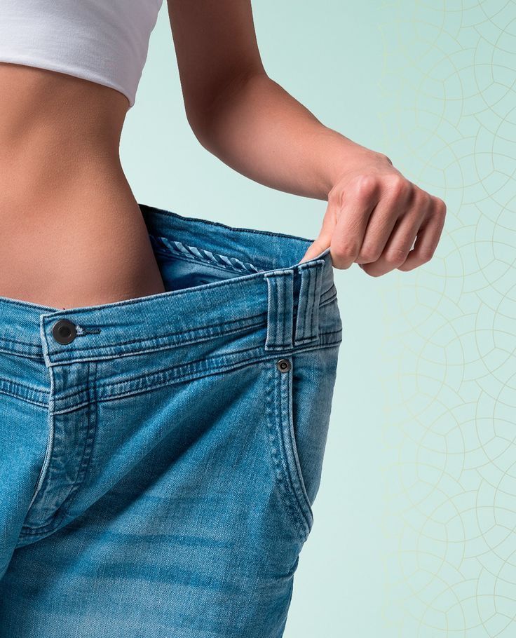 Person pulling the waistband of loose blue jeans to show extra room in the pants